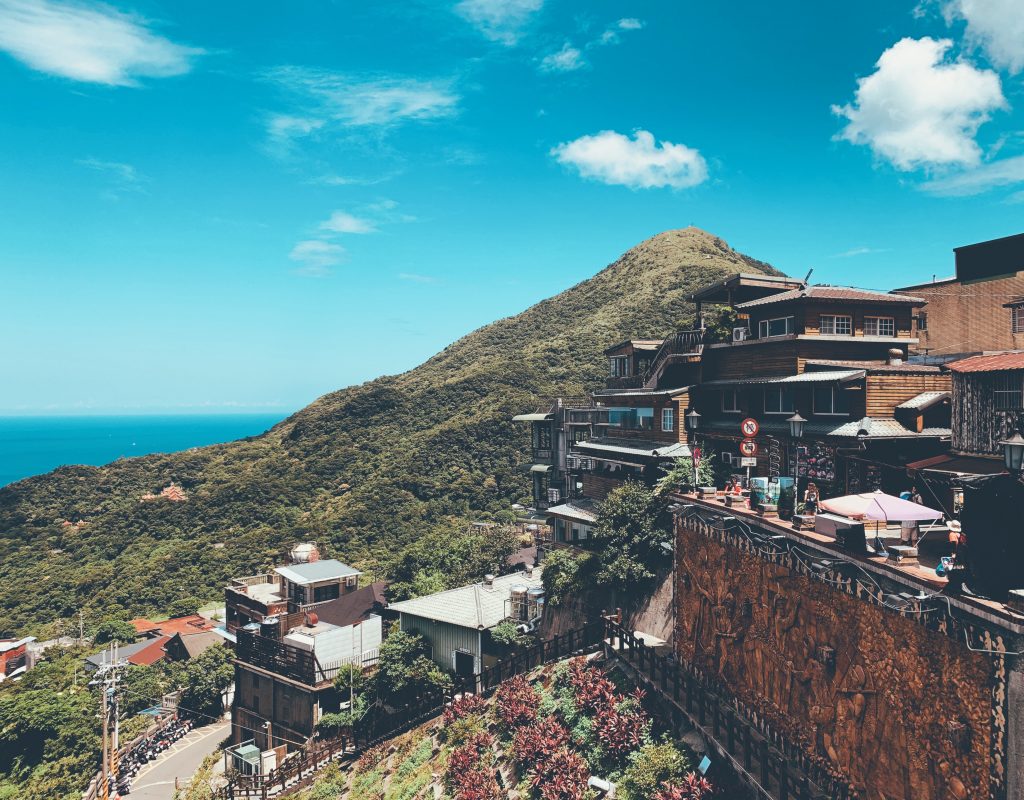 houses near mountain under blue and white skies during daytime